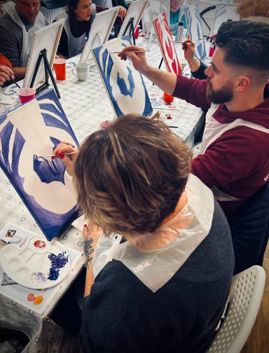 Participants painting on canvases at a creative workshop.